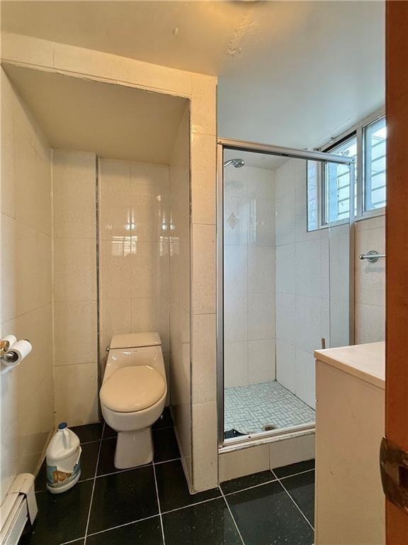 bathroom with toilet, tile patterned flooring, a baseboard radiator, and a shower stall