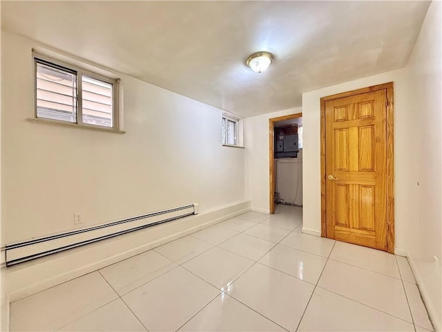 empty room featuring a baseboard heating unit, baseboards, and light tile patterned floors