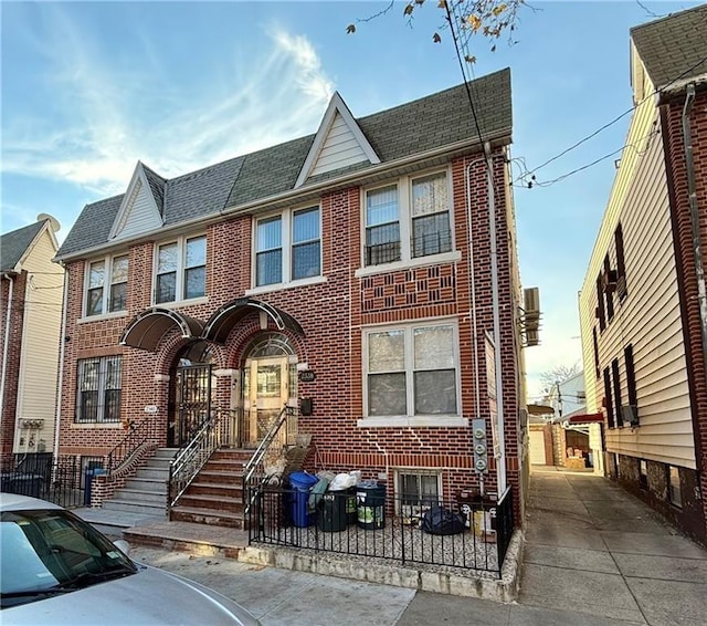 multi unit property with brick siding and a shingled roof