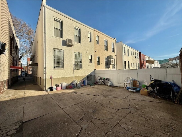 view of property with a wall mounted air conditioner and fence