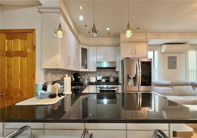 kitchen featuring a wall unit AC, under cabinet range hood, white cabinets, appliances with stainless steel finishes, and decorative backsplash