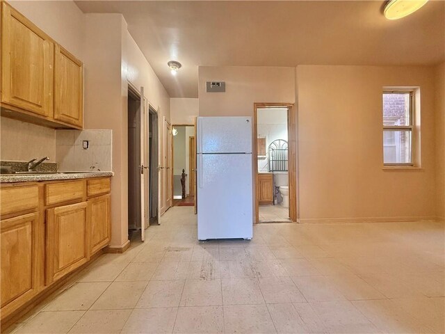 kitchen with white refrigerator, backsplash, sink, and light brown cabinets