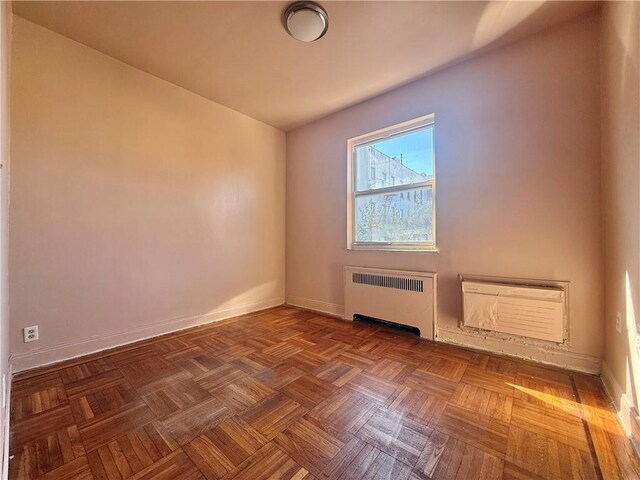 additional living space with parquet flooring, radiator heating unit, and a wall mounted AC