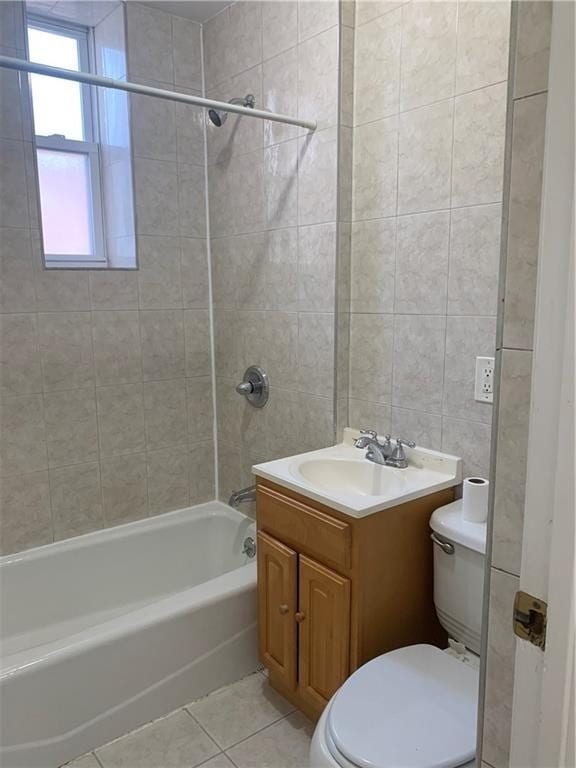 full bathroom with vanity, tile walls, tile patterned flooring, toilet, and tiled shower / bath