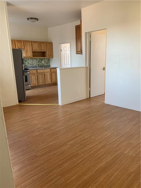 kitchen featuring light wood-type flooring, appliances with stainless steel finishes, and backsplash