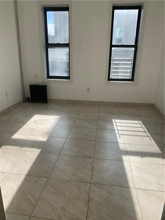 unfurnished room with radiator heating unit and light tile patterned floors