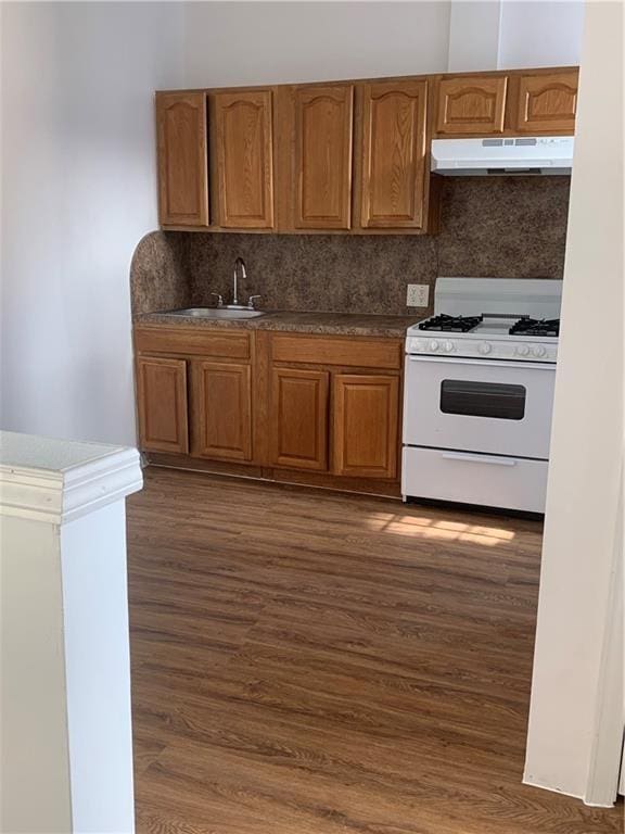 1738 79th St, Brooklyn, NY 11214 - kitchen featuring under cabinet range hood, white range with gas cooktop, a sink, decorative backsplash, and dark wood-style flooring