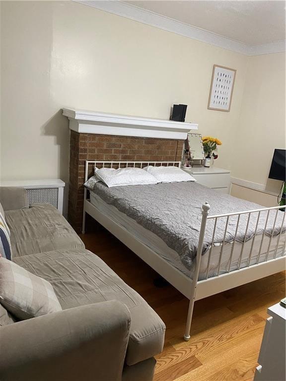 bedroom featuring a fireplace, hardwood / wood-style floors, and ornamental molding