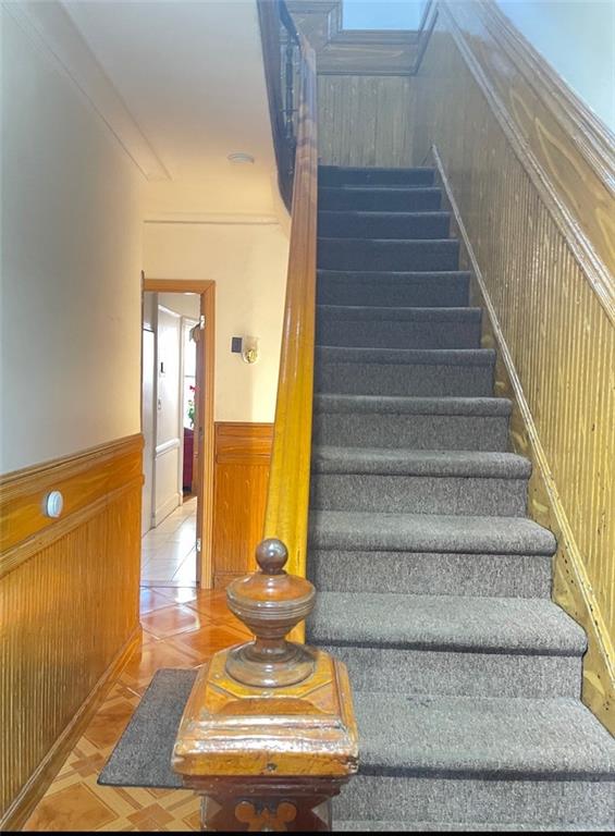 stairs with wood walls and ornamental molding