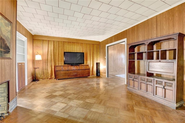 unfurnished living room featuring light parquet flooring, crown molding, and wood walls