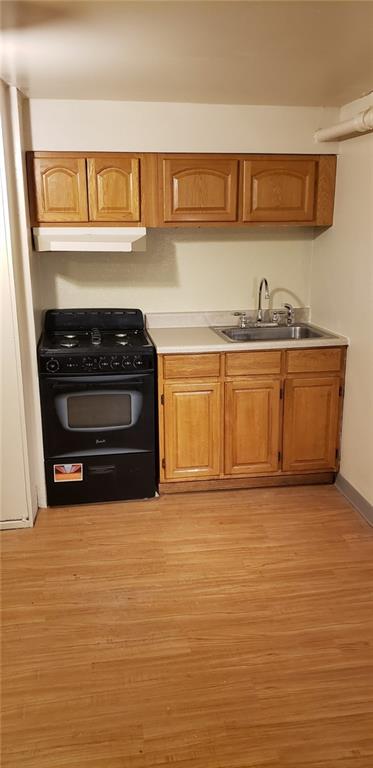 kitchen with light wood-type flooring, black gas range, and sink