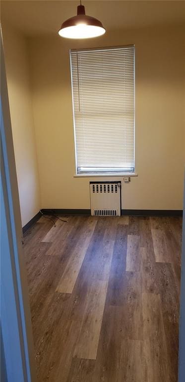 empty room with radiator heating unit and dark hardwood / wood-style floors