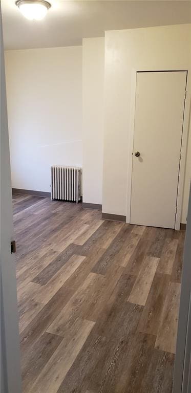 unfurnished room featuring radiator and dark hardwood / wood-style flooring