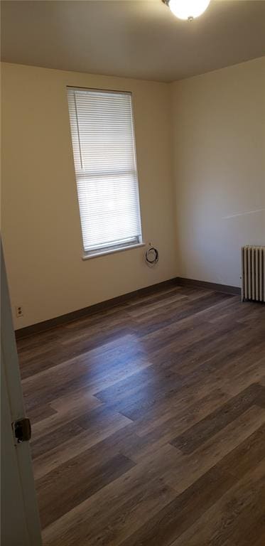 unfurnished room with radiator and dark wood-type flooring