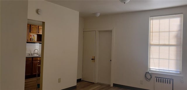 unfurnished bedroom featuring multiple windows, radiator heating unit, dark hardwood / wood-style flooring, and a closet