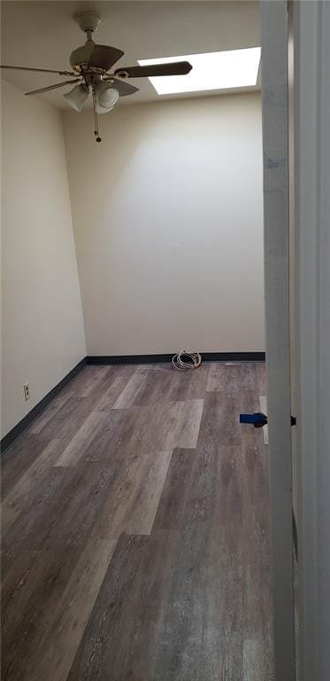 unfurnished room with a skylight, ceiling fan, and dark hardwood / wood-style flooring