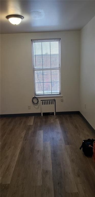 empty room featuring dark wood-type flooring and radiator