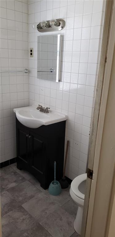 bathroom featuring tile walls, toilet, and vanity