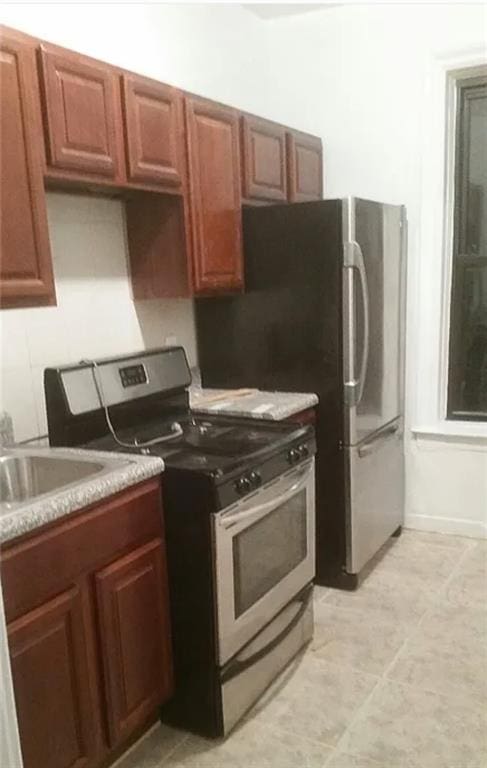 kitchen with light countertops, stainless steel electric range oven, and a sink