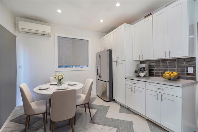 kitchen with white cabinetry, stainless steel fridge, and an AC wall unit