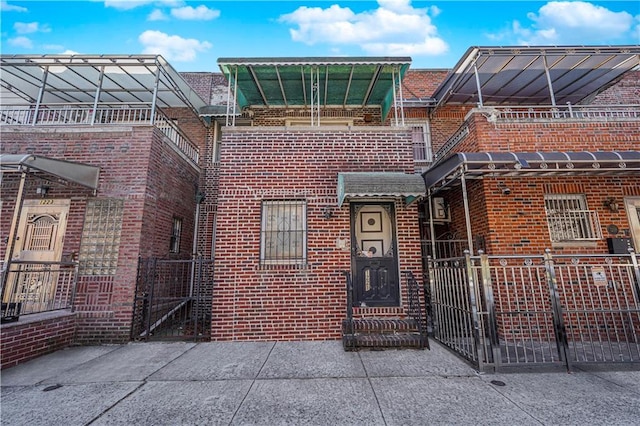 view of property featuring brick siding, a fenced front yard, and a gate