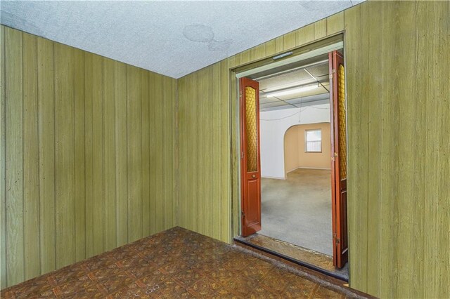 empty room with a textured ceiling and wooden walls