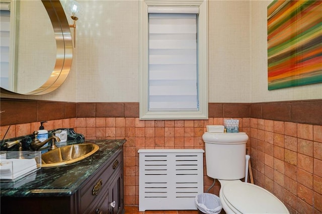 bathroom with vanity, toilet, and tile walls