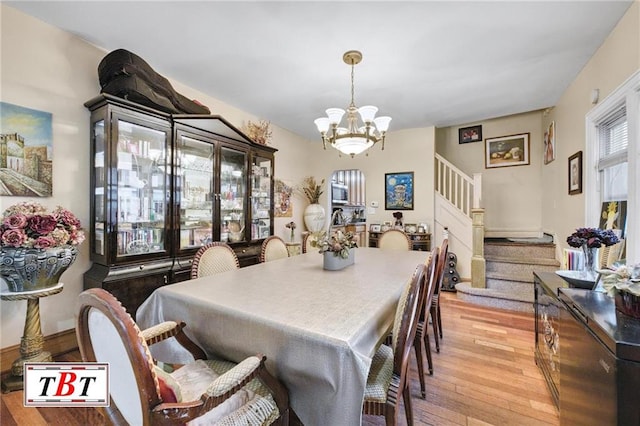 dining space with light hardwood / wood-style floors and a notable chandelier