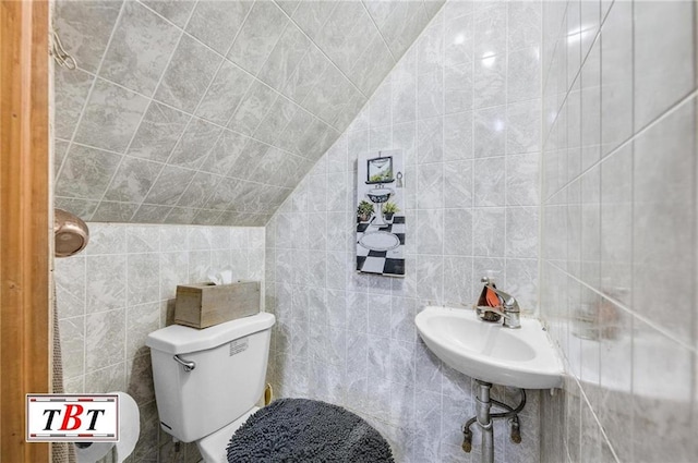 bathroom with tile walls, sink, vaulted ceiling, and toilet