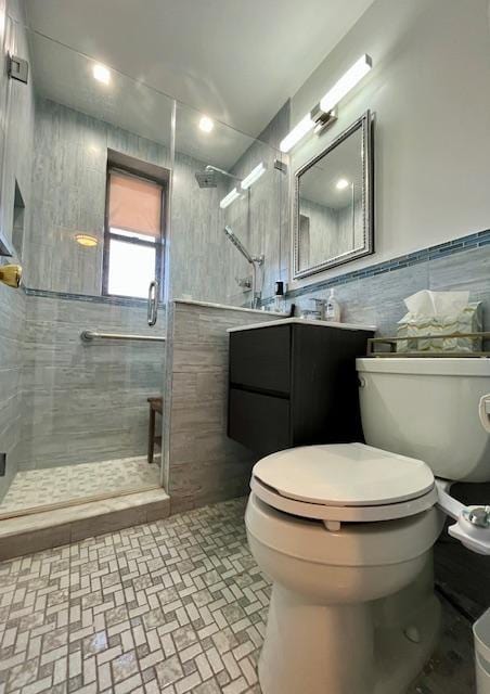 bathroom with vanity, a shower with door, toilet, and tile walls