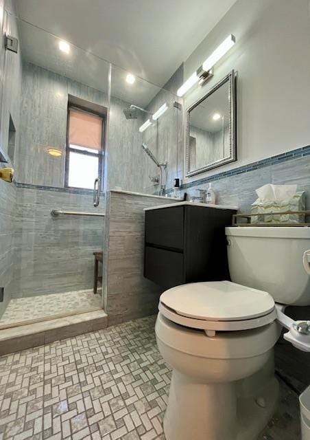 bathroom with a shower stall, toilet, tile walls, vanity, and brick patterned floors