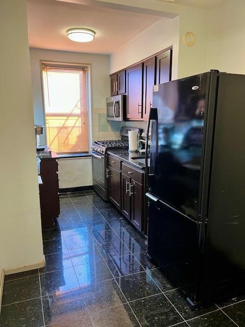 kitchen featuring stainless steel appliances, granite tiled floors, dark countertops, and baseboards