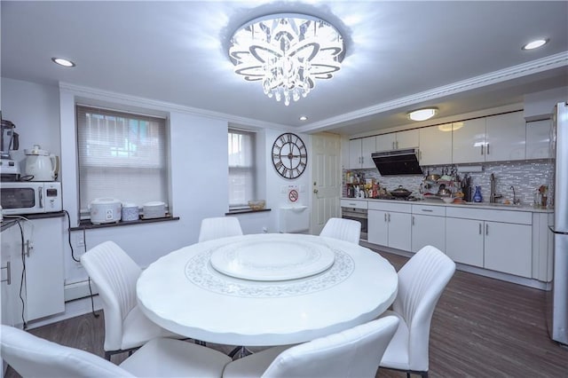 dining room featuring crown molding, dark hardwood / wood-style flooring, a chandelier, and sink