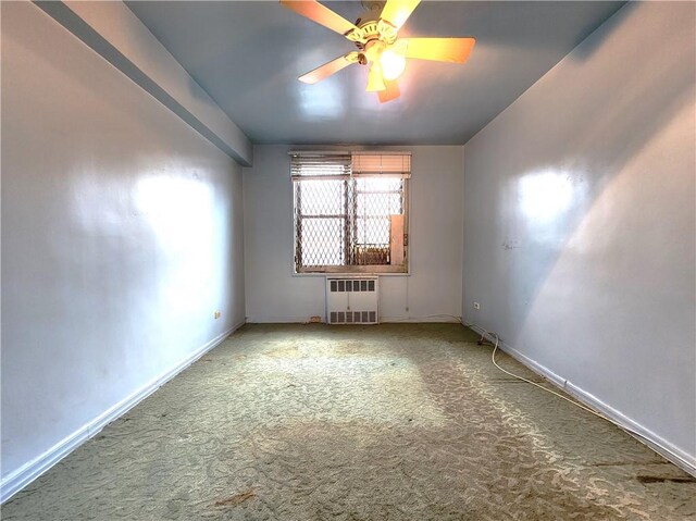 carpeted spare room featuring radiator and ceiling fan