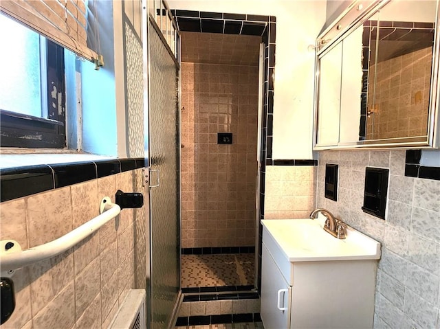 bathroom featuring tasteful backsplash, tiled shower, vanity, and tile walls