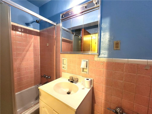 bathroom with tiled shower / bath, vanity, and tile walls