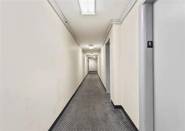 corridor with dark colored carpet and crown molding