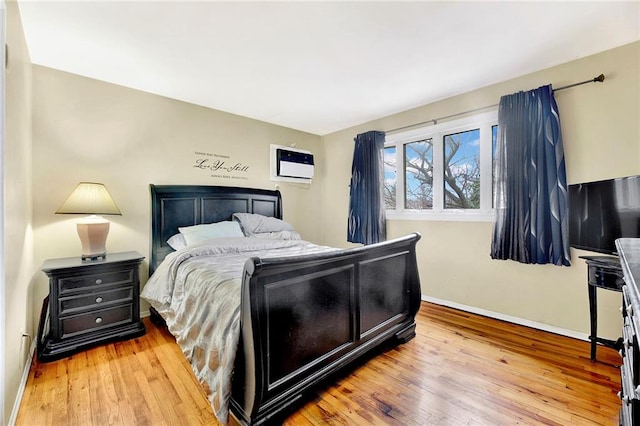 bedroom featuring light hardwood / wood-style flooring and a wall mounted air conditioner