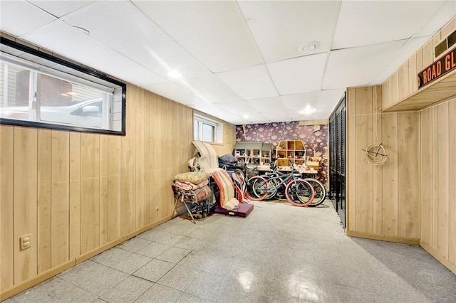 basement featuring a paneled ceiling and wood walls