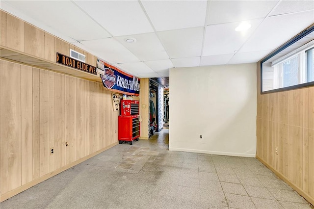 basement with wood walls and a drop ceiling