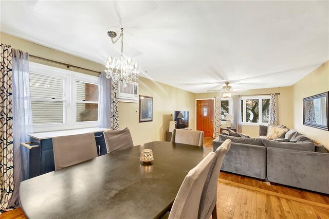 dining area featuring ceiling fan with notable chandelier, light hardwood / wood-style floors, and an AC wall unit