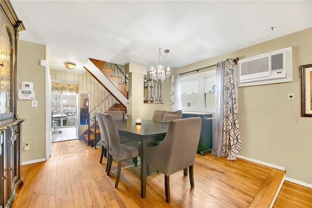 dining room with a notable chandelier, light hardwood / wood-style floors, and a wall unit AC