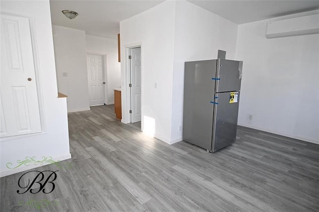 kitchen featuring hardwood / wood-style flooring, stainless steel refrigerator, and a wall mounted AC