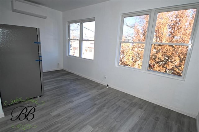 empty room featuring dark wood-type flooring, plenty of natural light, and an AC wall unit