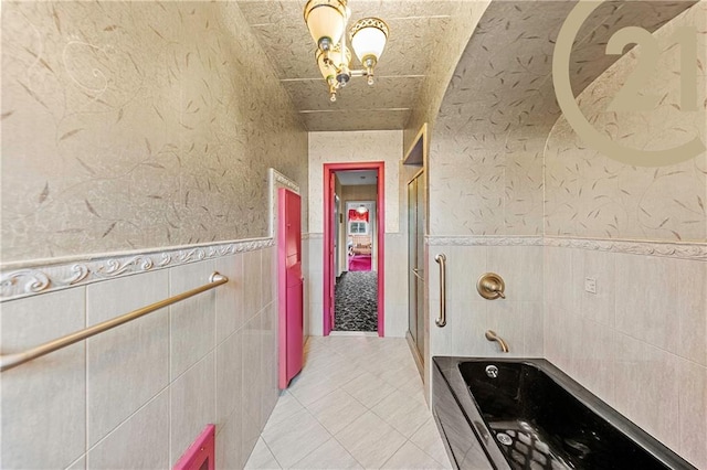 full bath with a wainscoted wall, tile patterned flooring, and a bath