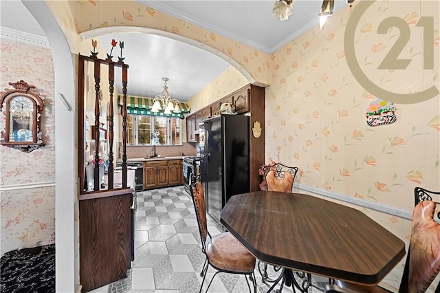 dining room featuring wallpapered walls, crown molding, arched walkways, and a notable chandelier