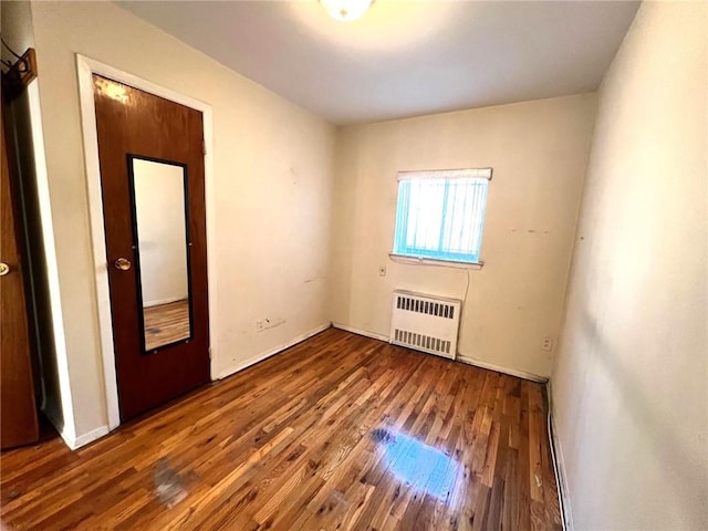 unfurnished room featuring dark hardwood / wood-style flooring and radiator