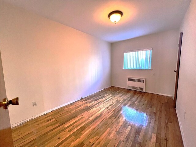 spare room with radiator and dark hardwood / wood-style floors