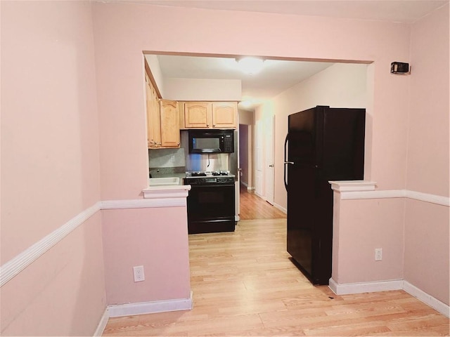 kitchen with light hardwood / wood-style flooring and black appliances