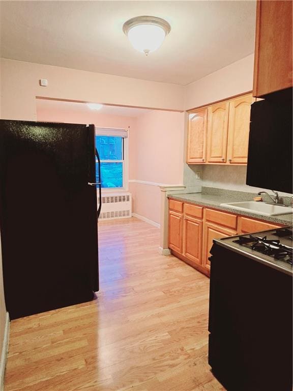 kitchen with black appliances, light hardwood / wood-style floors, sink, and light brown cabinetry